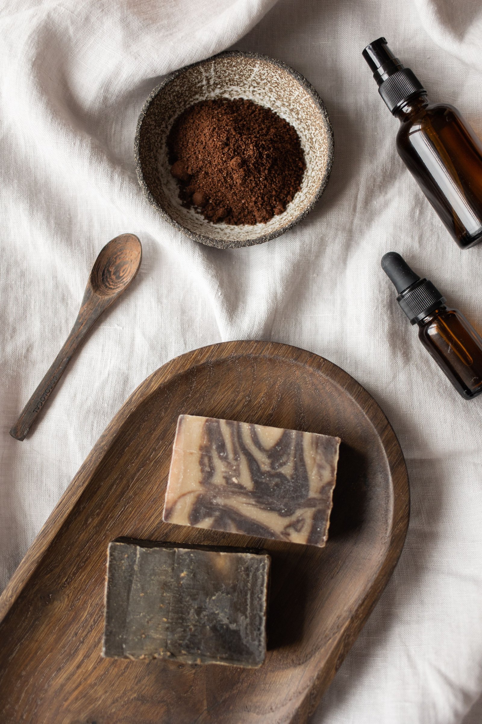 Warm autumn self-care flatlay with essential oils, candle and botanicals on linen — NINÜ
